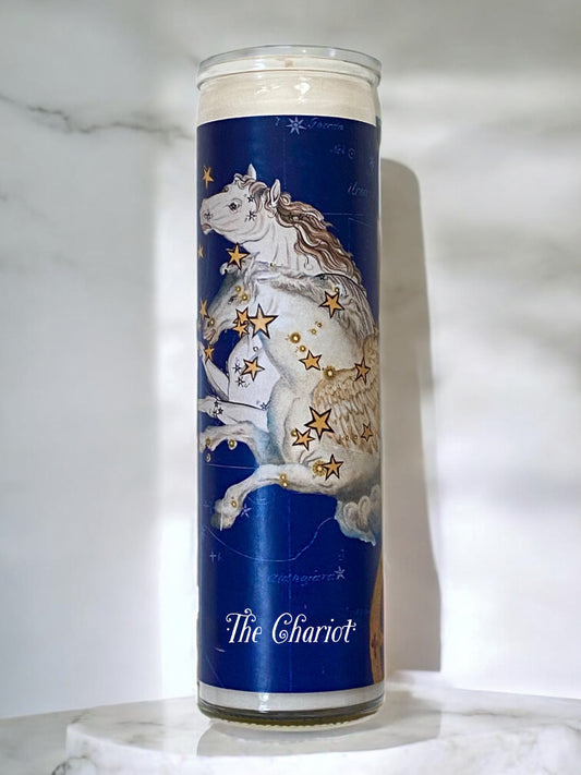 Candle with a design of a horse and stars on a blue background, placed on a marble surface.