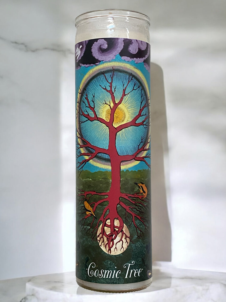 Candle with 'Cosmic Tree' design on a white marble surface