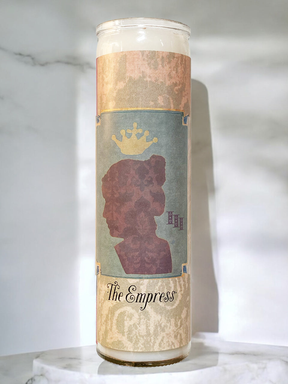 Candle labeled 'The Empress' with a silhouette design on a marble surface.