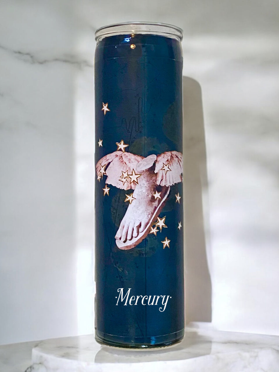 Candle with a winged foot design and 'Mercury' text on a marble surface