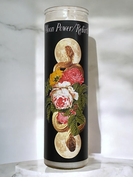 Candle with decorative label featuring flowers and moon phases on a marble surface.