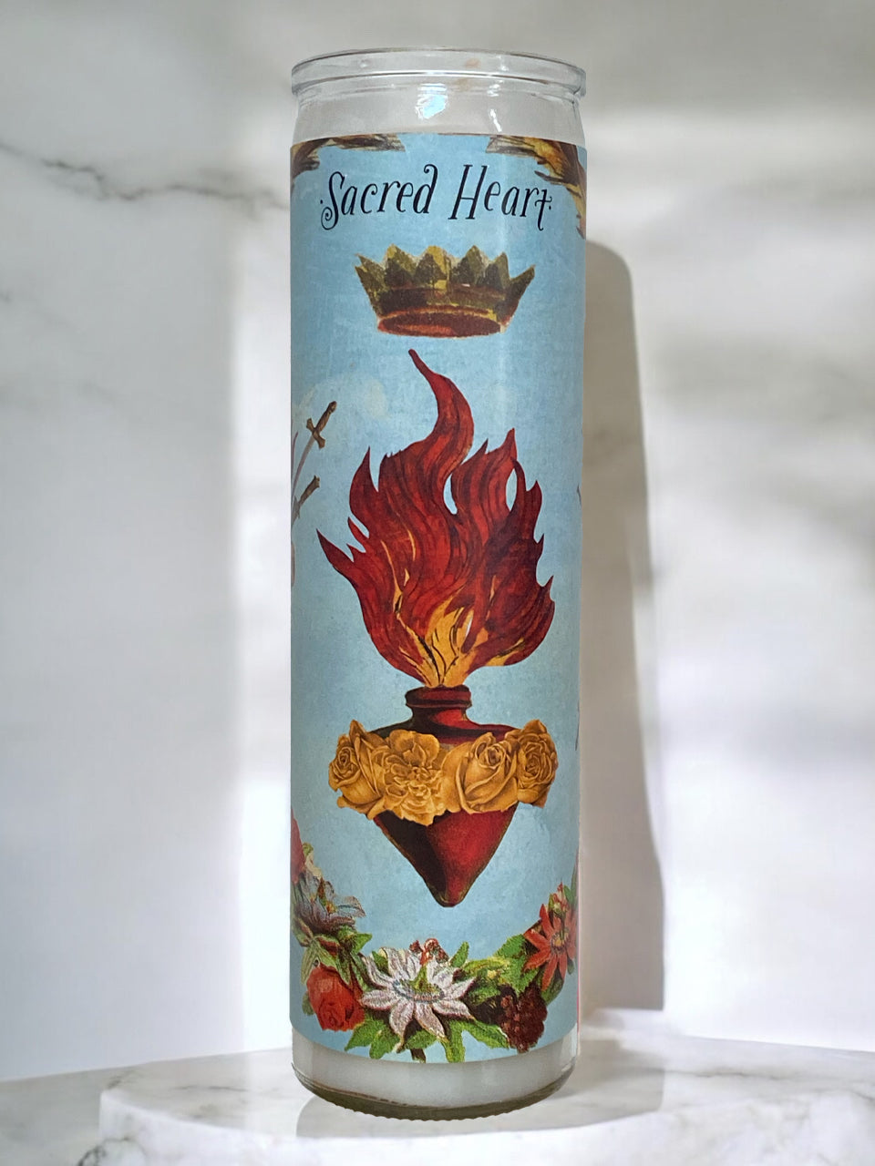 Candle with 'Sacred Heart' design on a light blue background