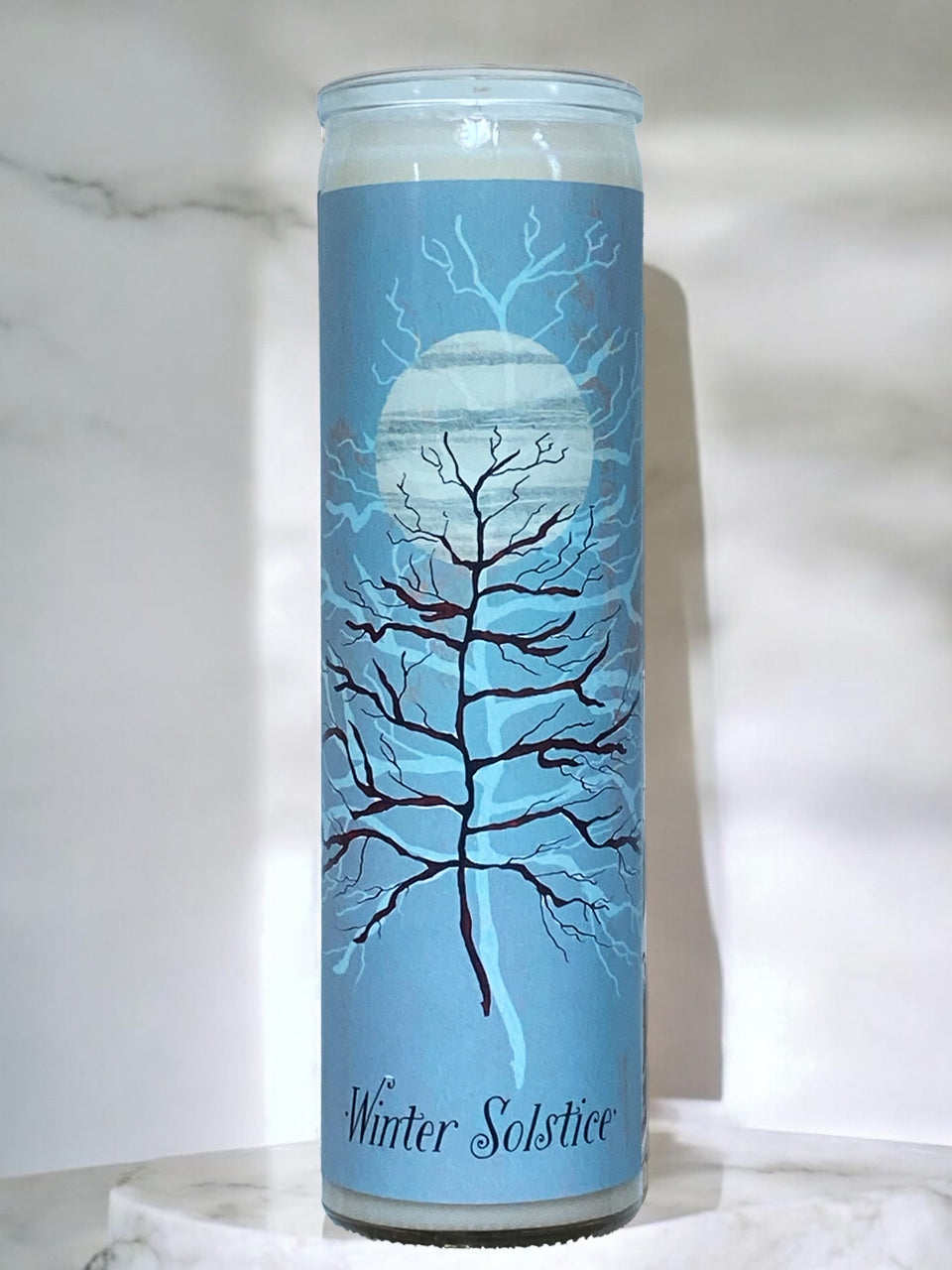 Candle with blue design and 'Winter Solstice' text on a marble surface