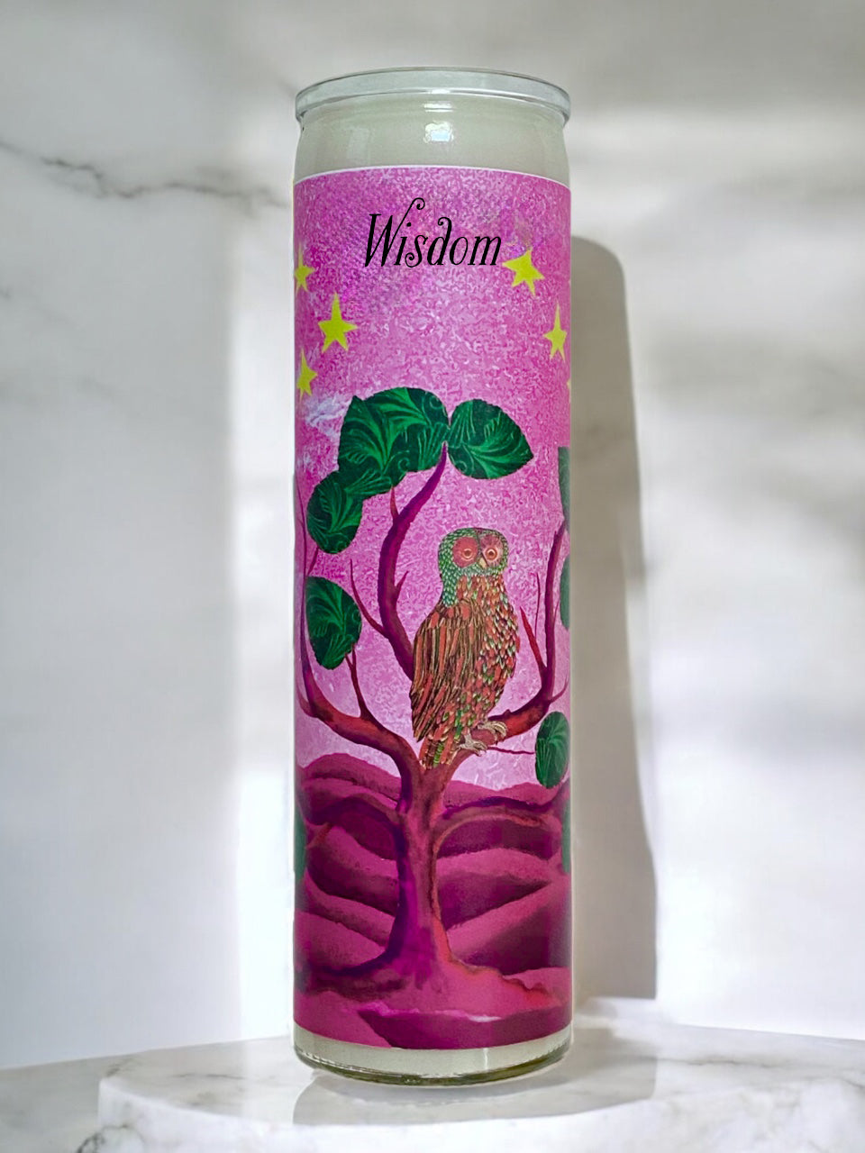 Candle with owl design and 'Wisdom' text on a pink background