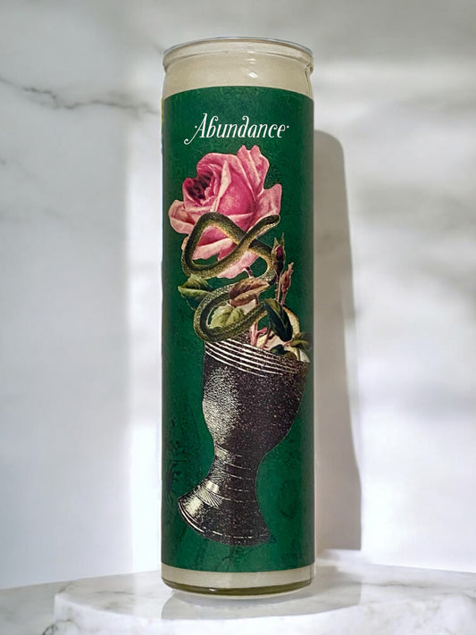 Candle displaying a rose and cup against a green background, with the word "abundance."