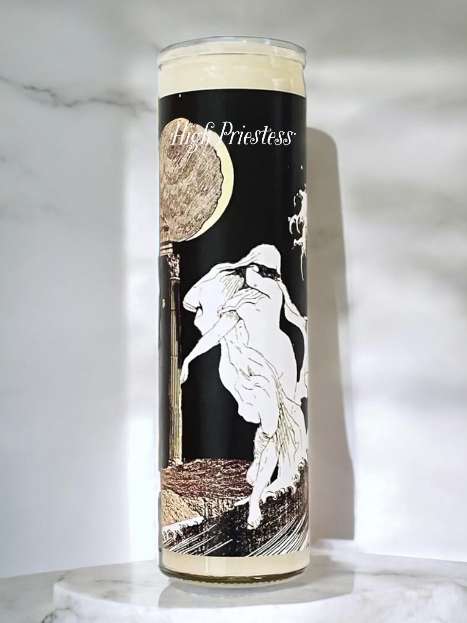Candle with a design of a woman and moon phases on a black background, placed on a marble surface.