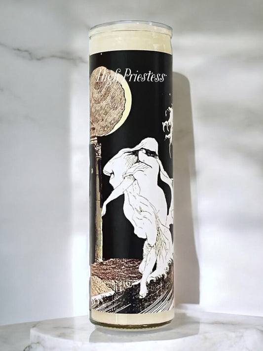 Candle with a design of a woman and moon phases on a black background, placed on a marble surface.