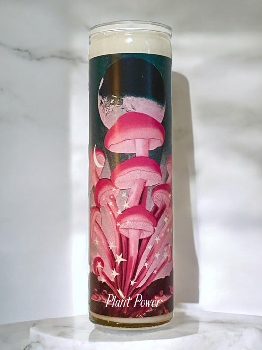 Candle with pink mushroom design and 'Plant Power' text on a white marble surface.