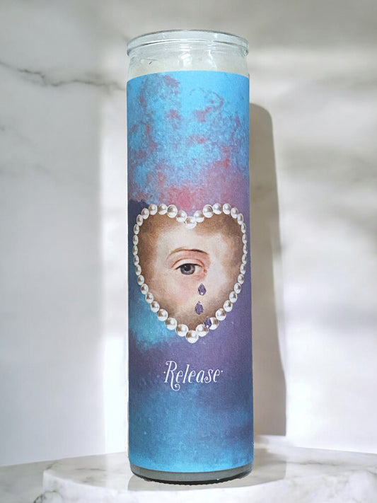 Candle with a design of a face with pearls and the word 'Release' on a blue background.