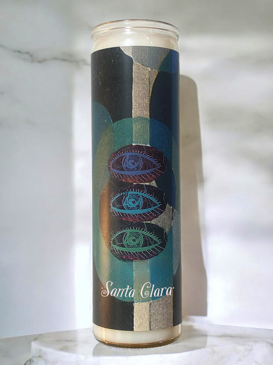 Candle with artistic design and 'Santa Clara' branding on a marble surface.