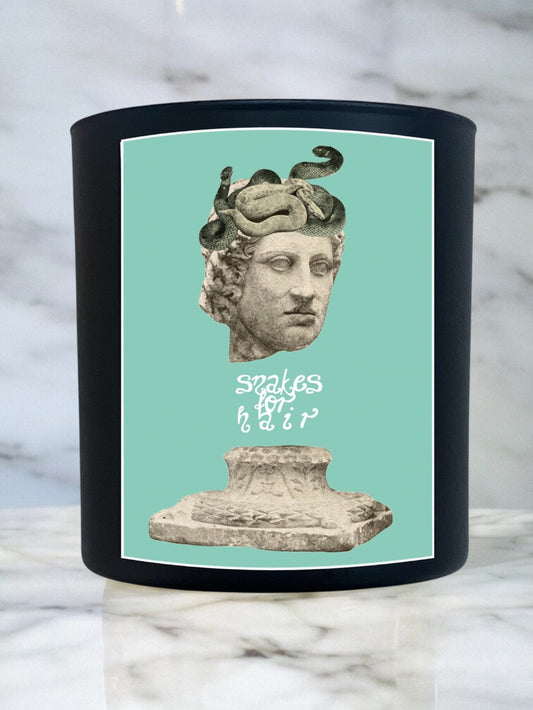 Candle with a decorative label featuring a classical sculpture on a marble surface