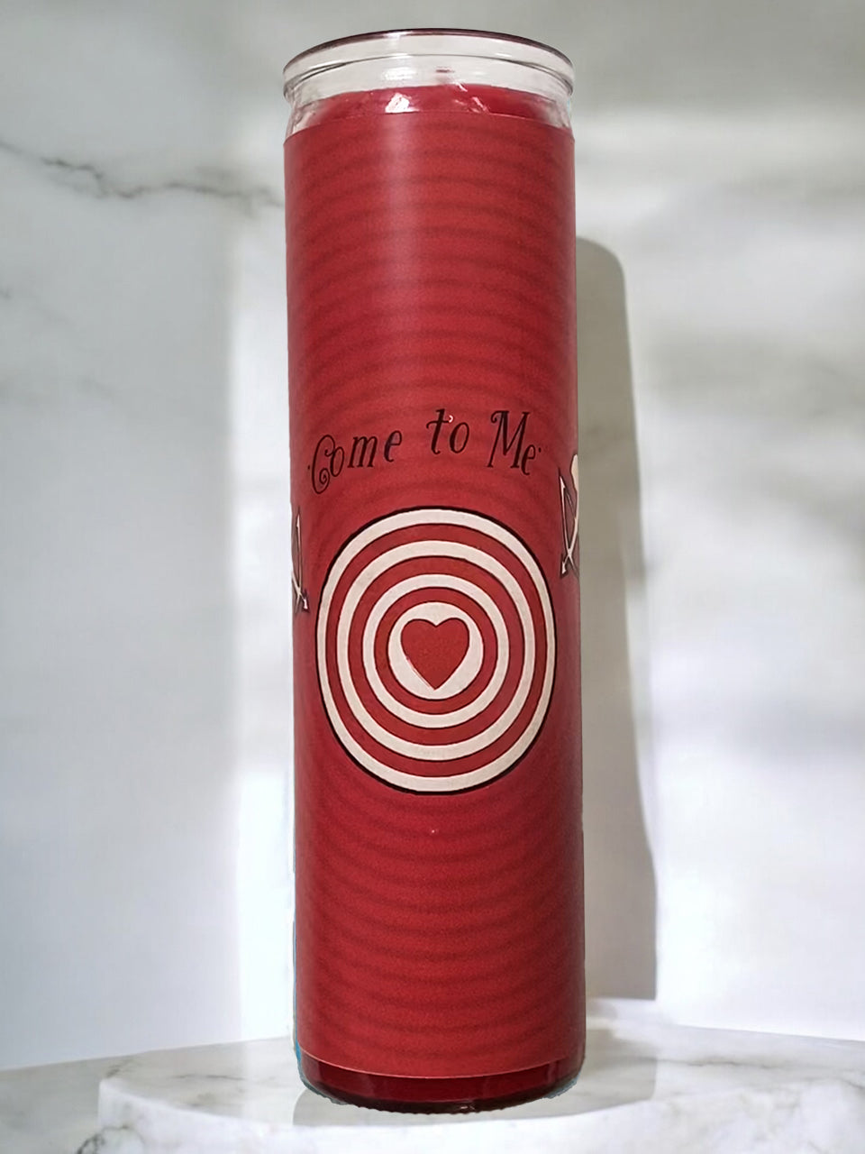 Red candle with text and a heart bullseye design on a white marble surface