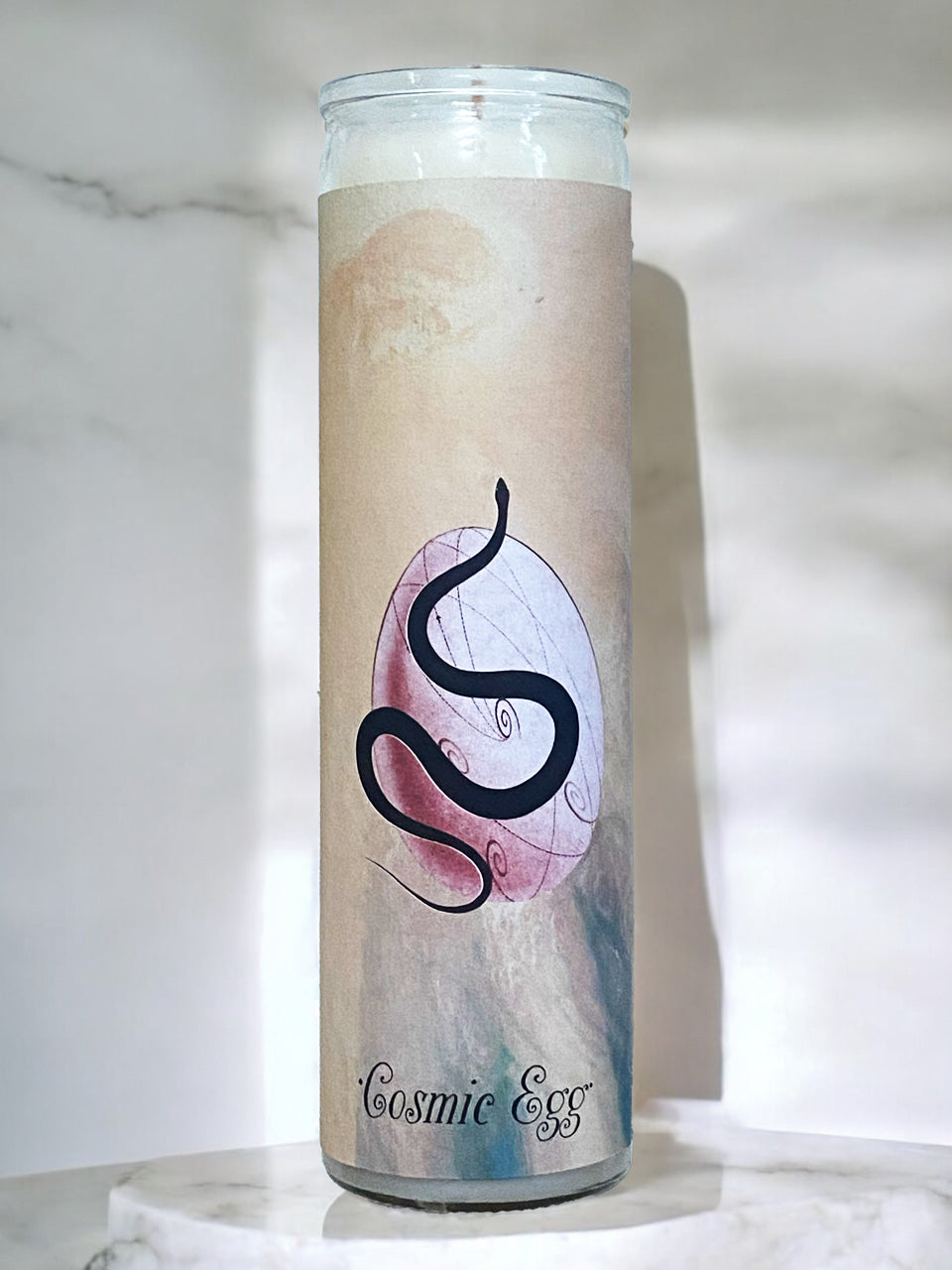 Candle with a design of a snake and egg on a marble surface
