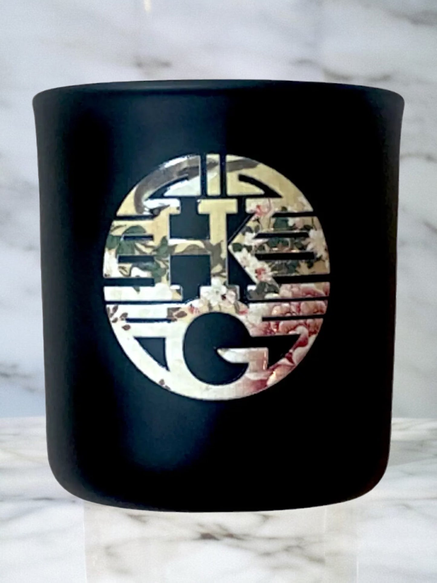 Black container with a decorative logo on a marble background