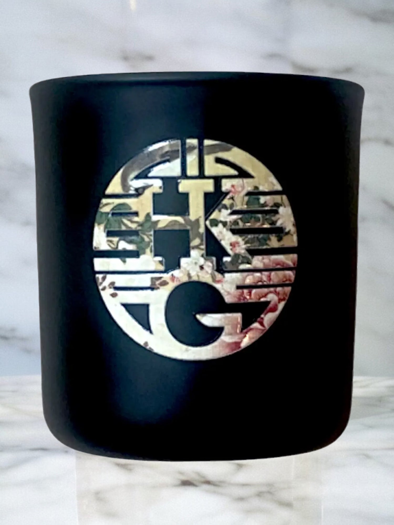 Black container with a decorative logo on a marble background